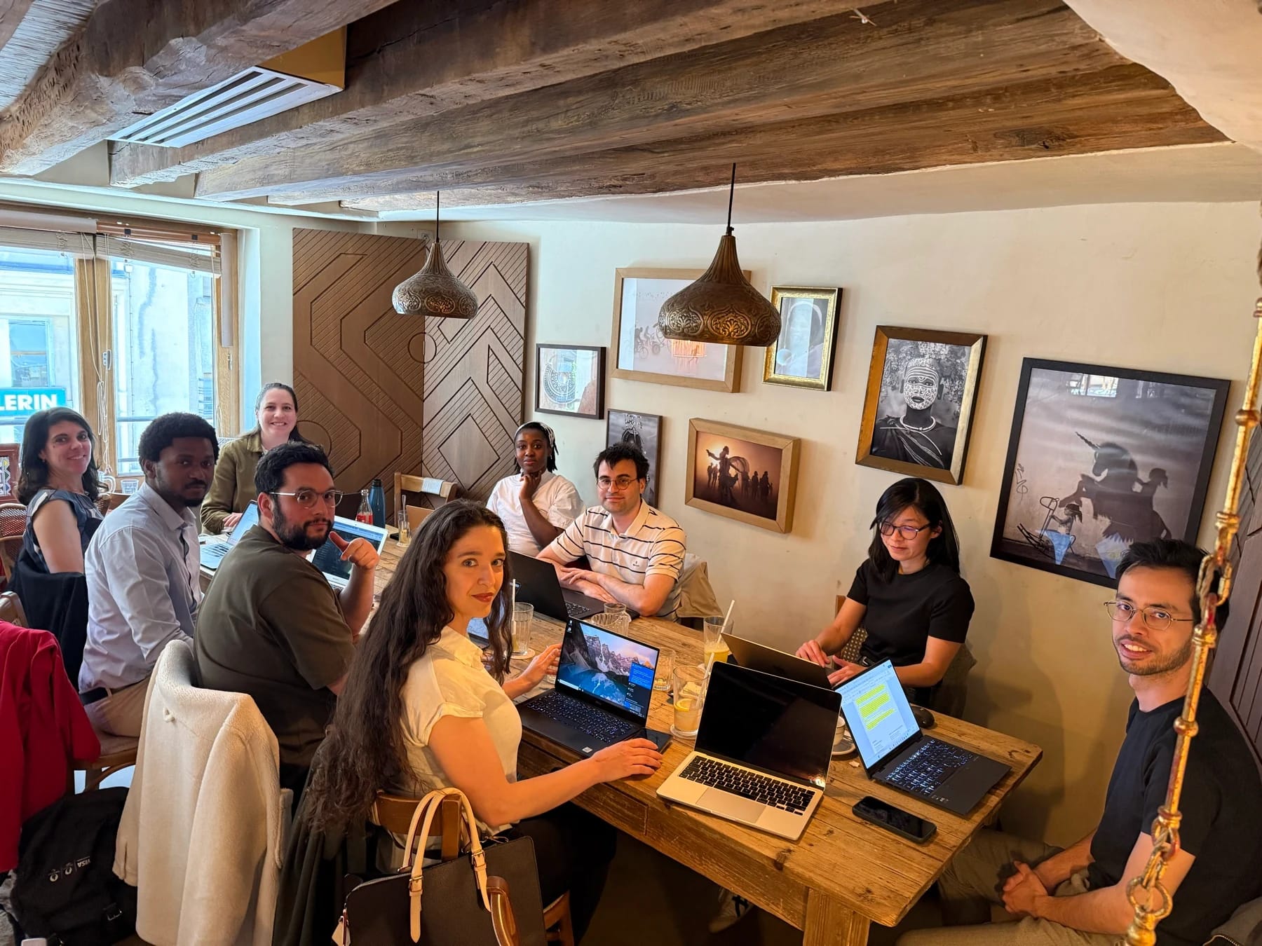 Des membres CoworkMeet réunis avec leurs ordinateurs autour d’une table dans un café chaleureux
